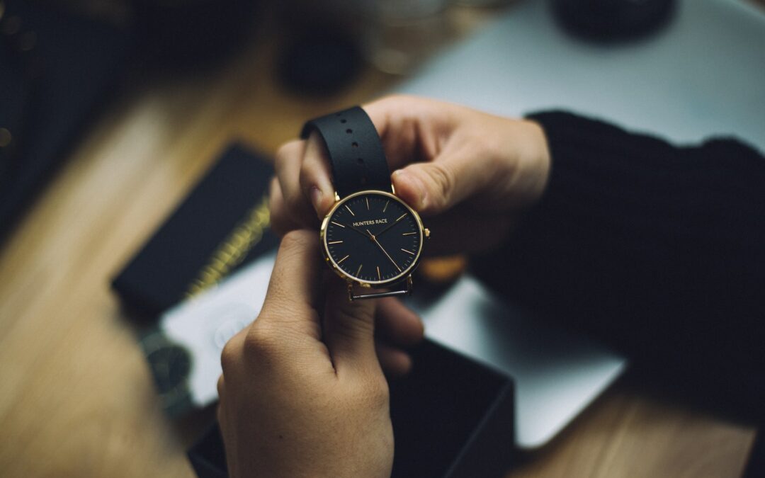 person holding gold-colored analog watch with black strap